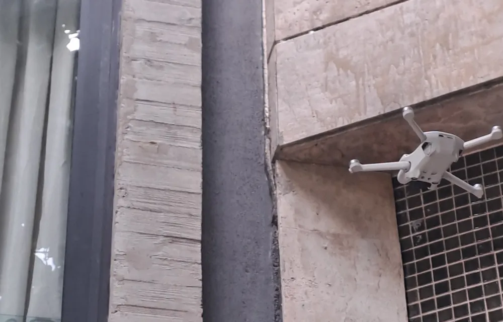 Drone em operação de inspeção próxima à fachada de um edifício